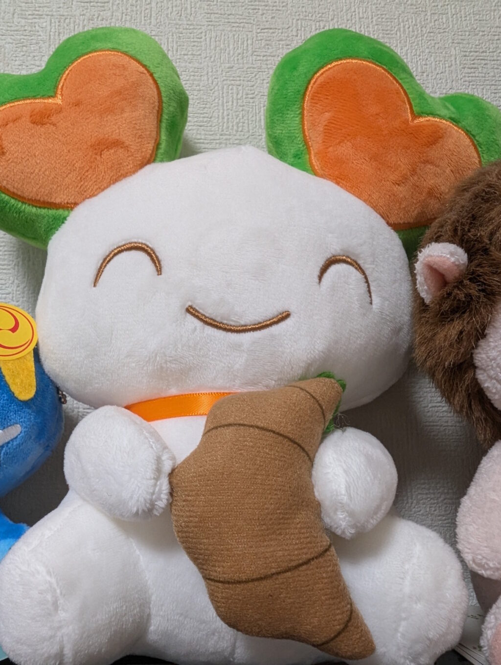 ララピーがミニクロワッサンを持っているお座りぬいぐるみ